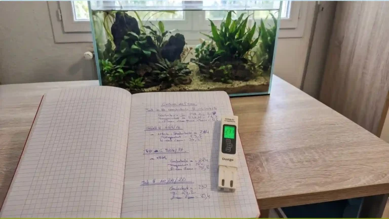Carnet de mesures d'évaporation aquarium avec conductimètre Dustgo affichant 231 µS, bac naturel low-tech en arrière-plan